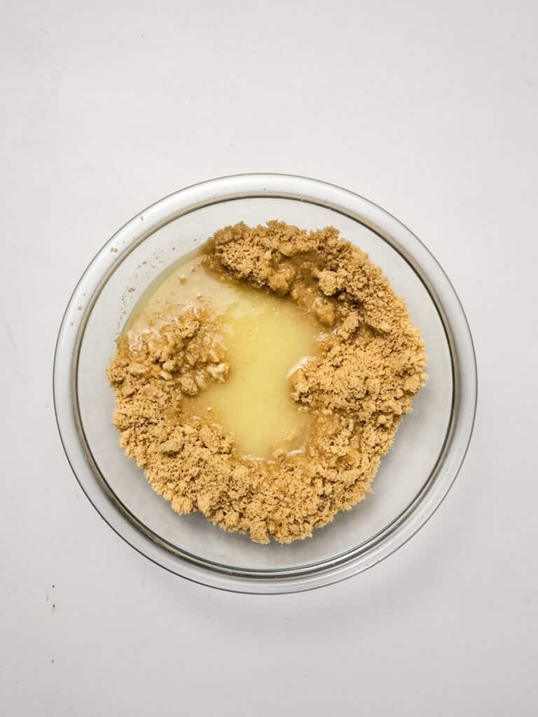 adding butter to golden oreos for strawberry crunch cheesecake