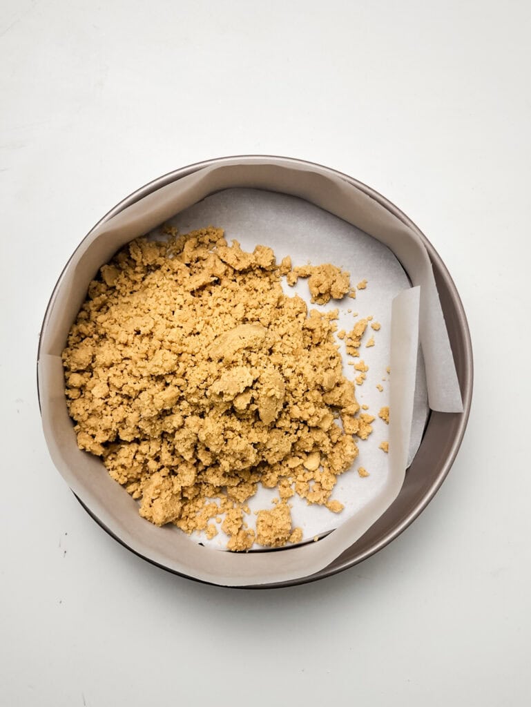 making golden oreo crust in springform pan for strawberry crunch cheesecake