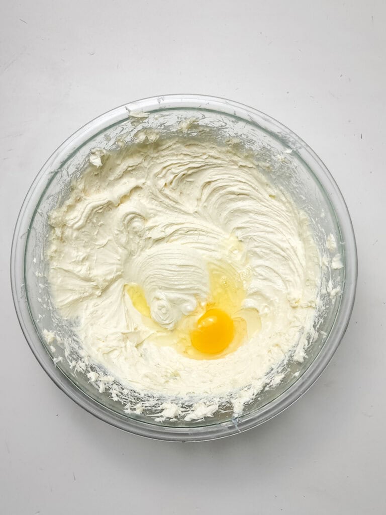 adding eggs to cheesecake filling for for strawberry crunch cheesecake