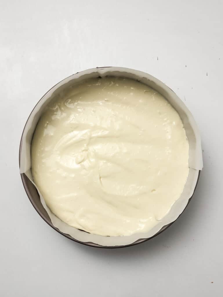 pouring filling into springform pan for for strawberry crunch cheesecake