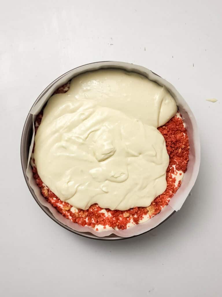adding more cheesecake filling to strawberry crunch cheesecake