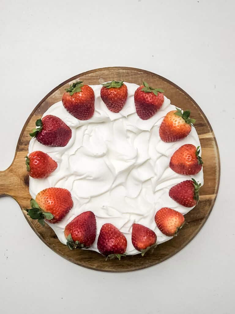 adding fresh strawberries to strawberry crunch cheesecake