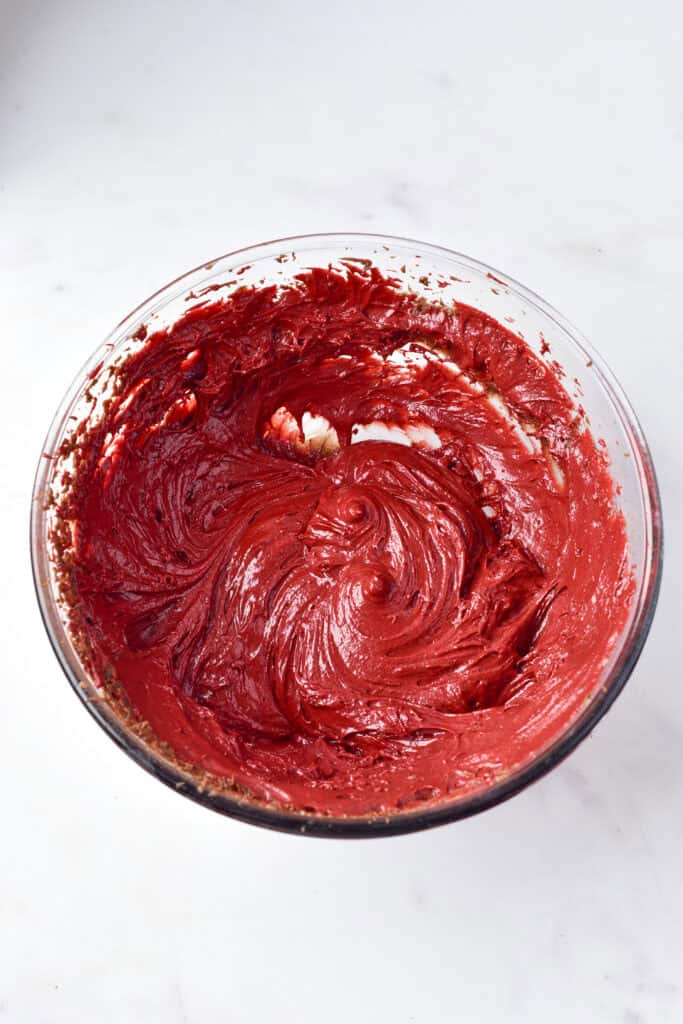 Smooth red velvet brownie batter swirled in a clear mixing bowl.