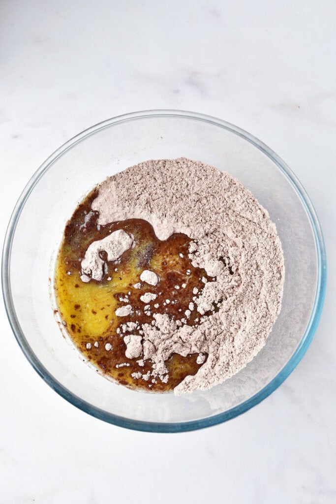 Cocoa flour and melted butter mixture starting to combine in a glass bowl.