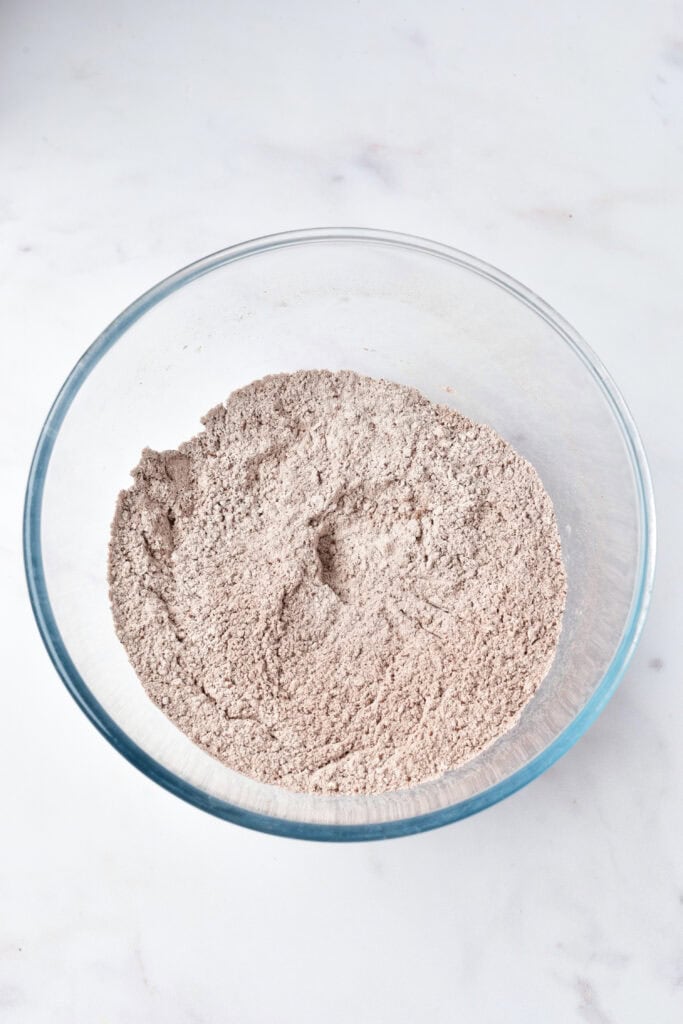 Dry red velvet brownie ingredients mixed in a glass bowl.