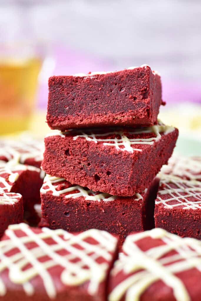 Stacked red velvet brownies drizzled with white chocolate.