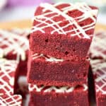 Red velvet brownies stacked and drizzled with white chocolate.