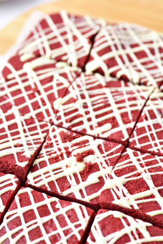 Close-up of sliced red velvet brownies topped with white chocolate drizzle.